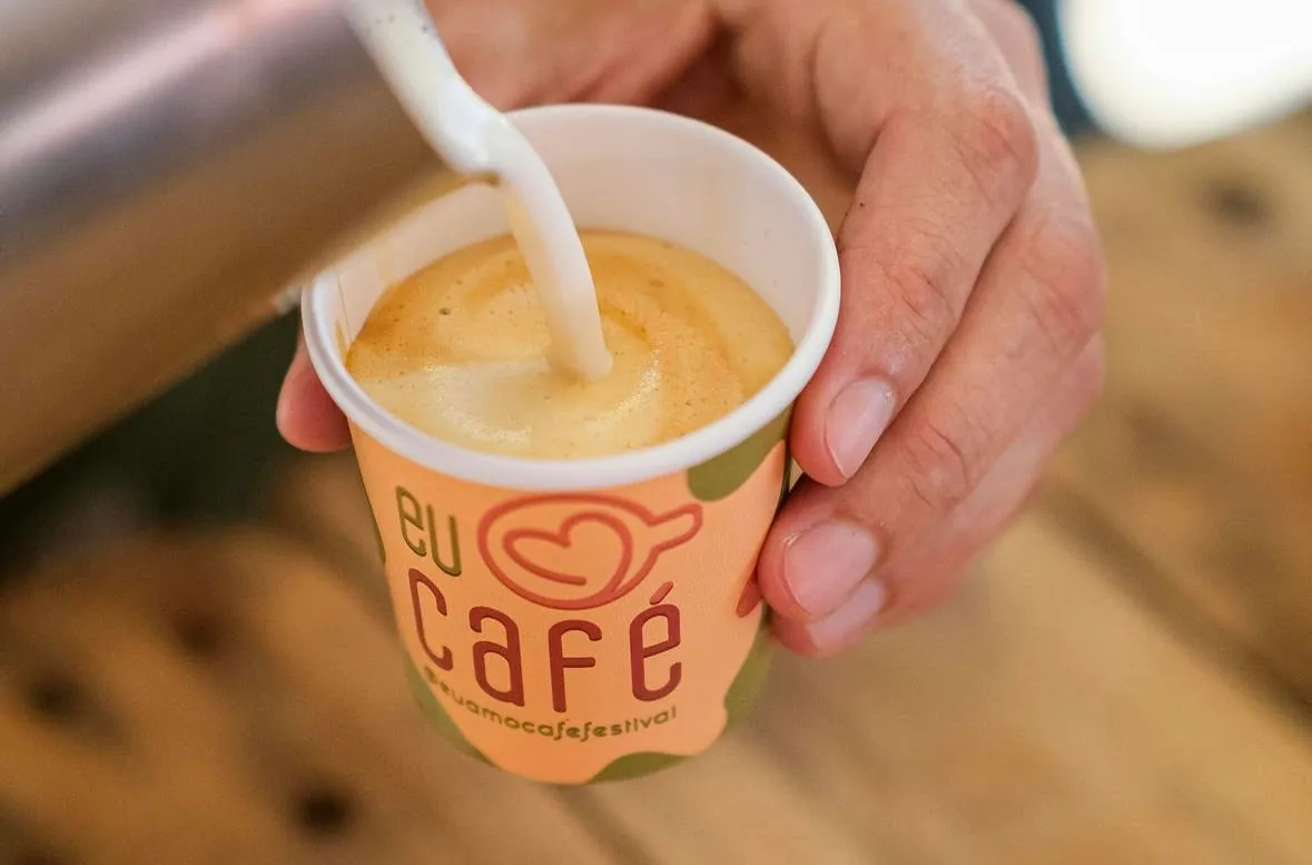 Leite sendo servido em um copo do Festival Eu Amo Café, em fotografia de divulgação de Filipe Ramos
