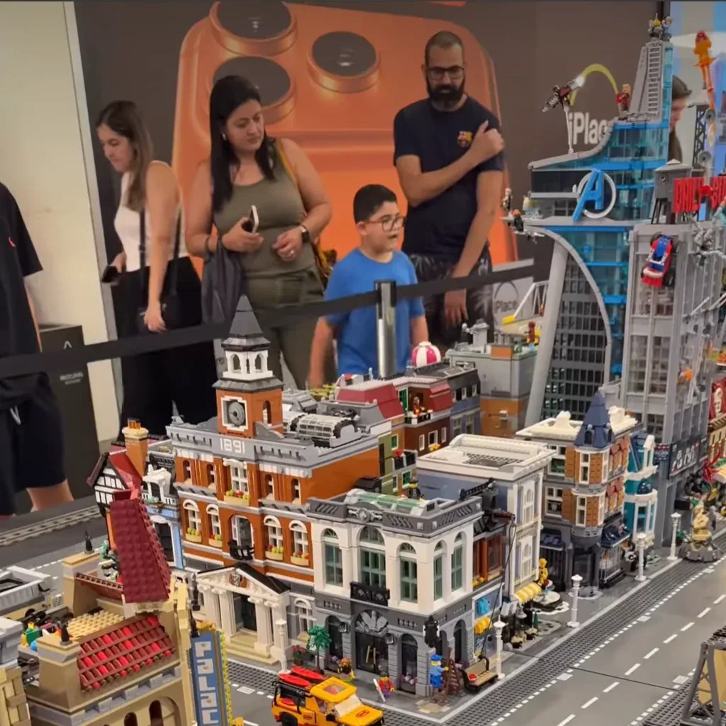 Cidade de LEGO inspirada em Gotham City, com arranha-céus iluminados, dirigíveis da polícia e o símbolo do Batman ao fundo