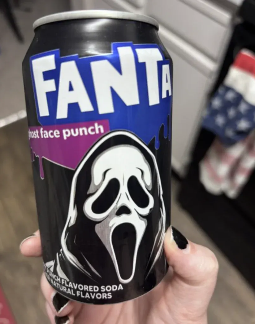 Lata de Fanta da edição de Halloween segurada na mão, com arte dos monstros da campanha