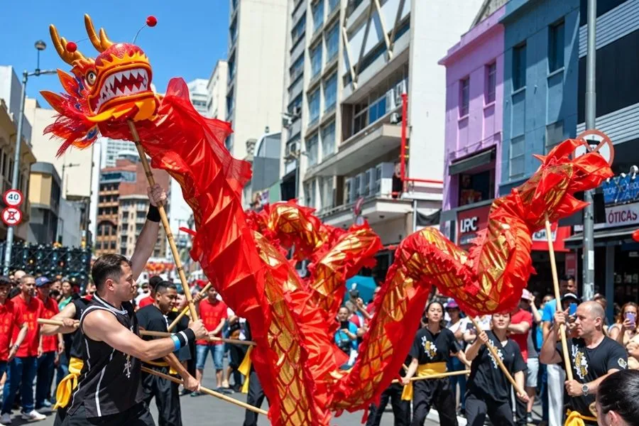 Dragão chinês vermelho e dourado sustentado por varas em apresentação na Rua 25 de Março