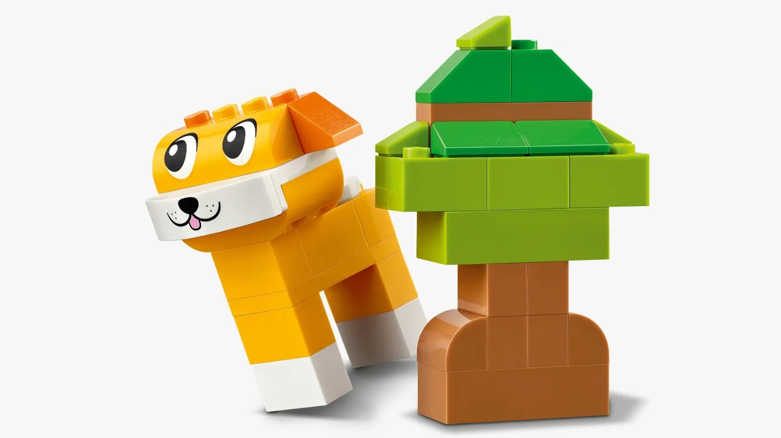 Cachorro amarelo de peças LEGO ao lado de uma árvore verde montada com blocos