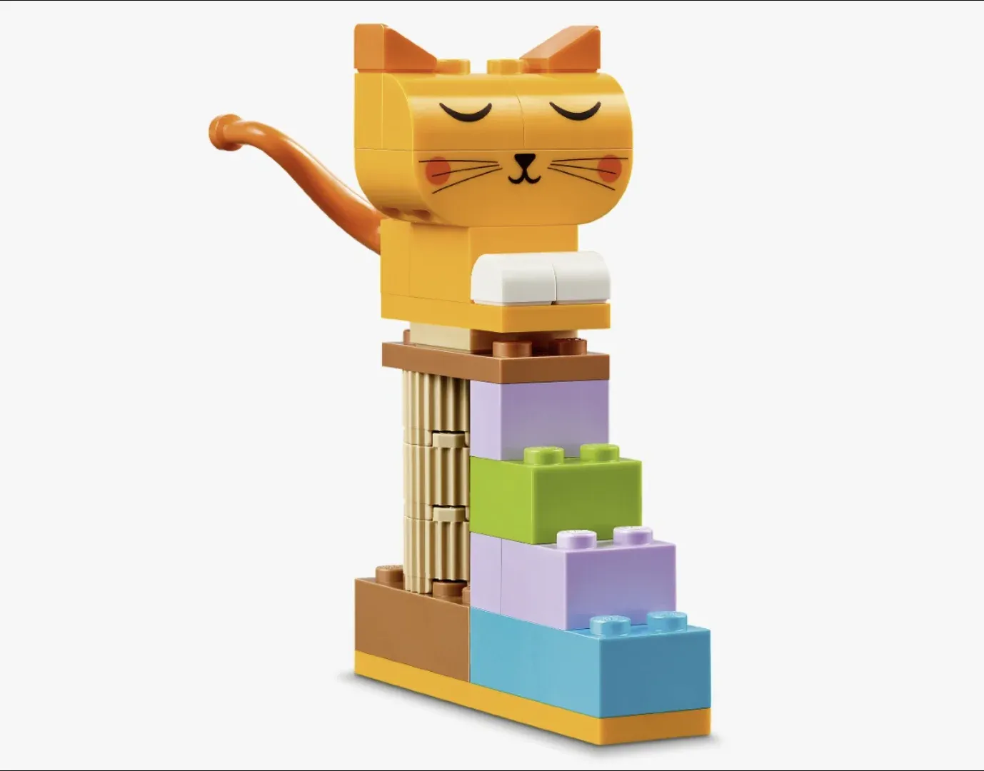 Gato laranja de peças LEGO com olhos fechados deitado sobre um arranhador de blocos coloridos