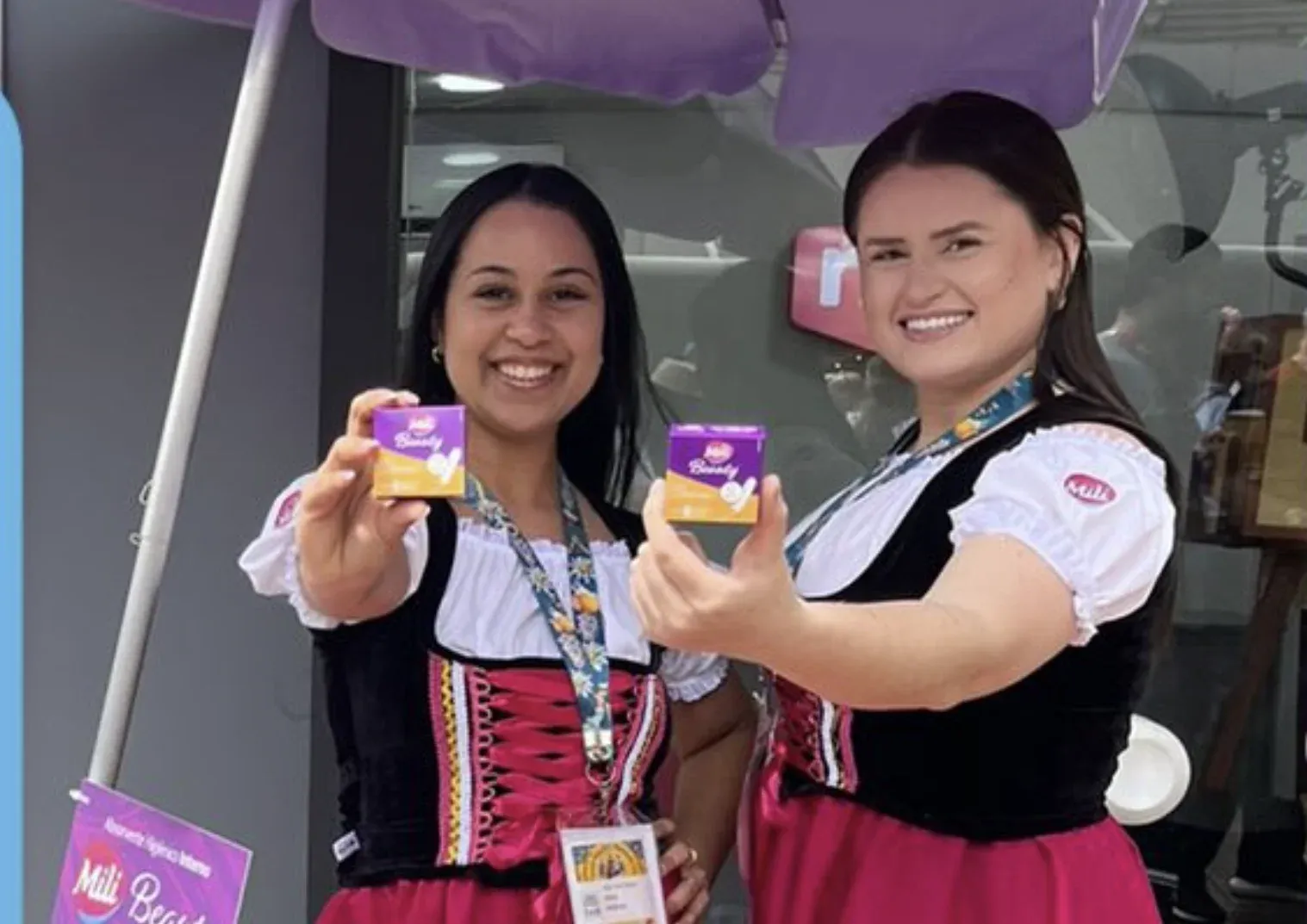 Promotoras da Mili em traje típico alemão mostrando caixinhas do absorvente interno Mili Beauty