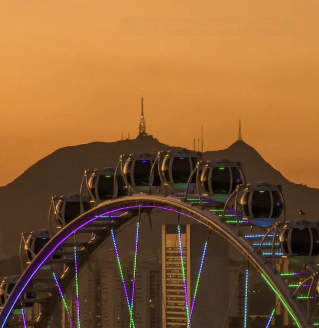 Cabines da Roda Rico com luzes coloridas e o Pico do Jaraguá ao fundo no fim de tarde