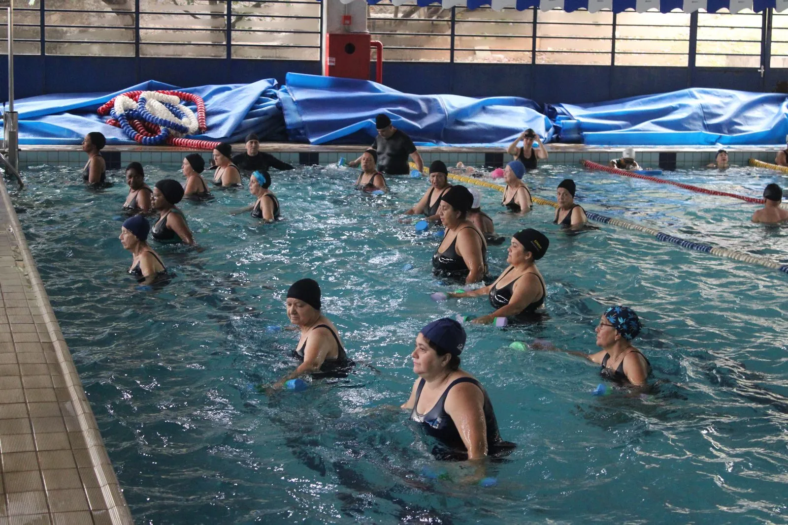 Turma em aula de hidroginástica na piscina de um centro esportivo municipal